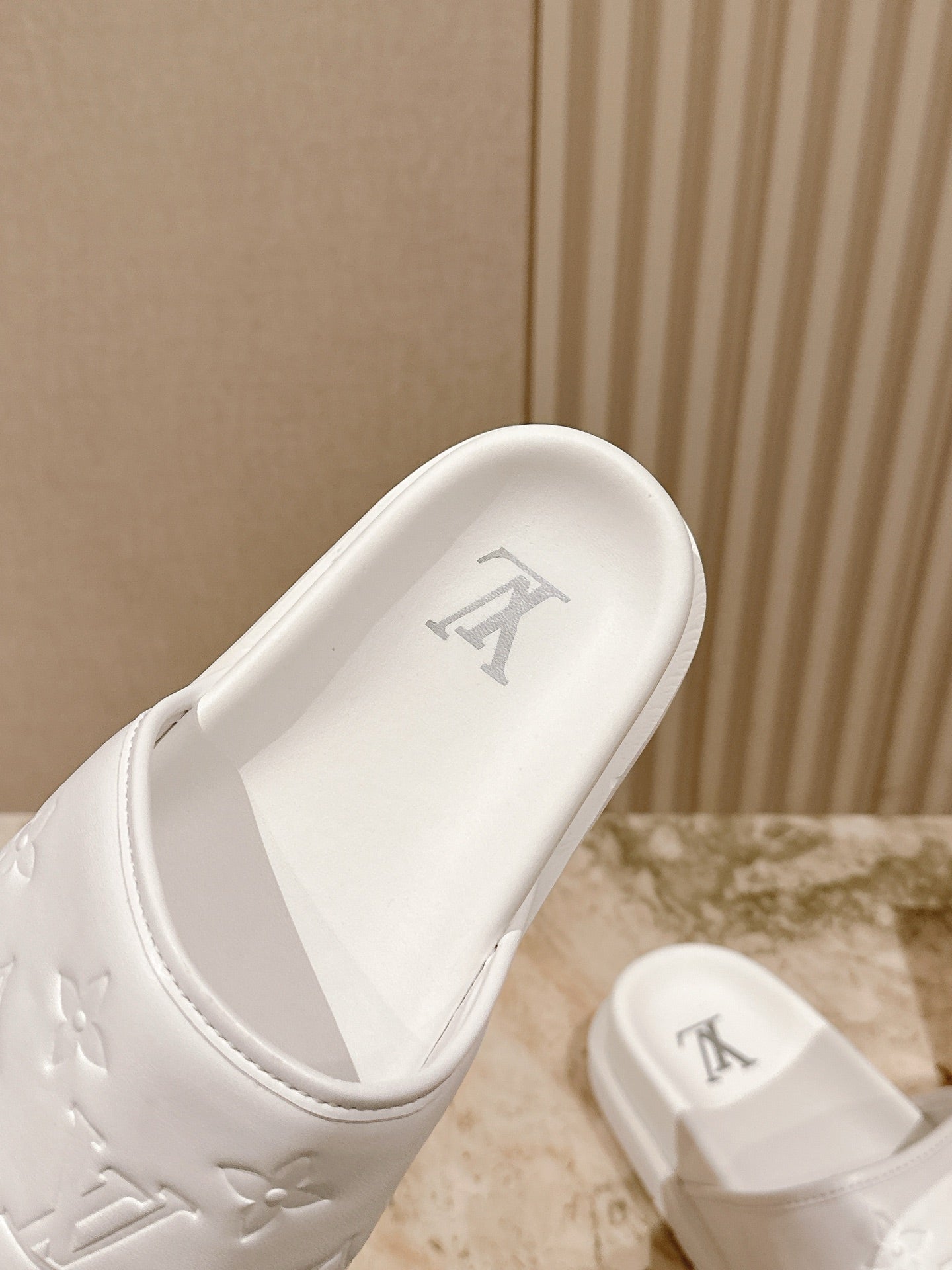 White sandal slide with padded strap and embossed LV initials on footbed