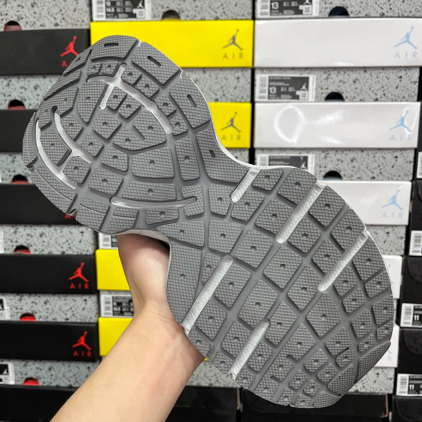 Unisex sneakers outsole in light gray with traction tread pattern, rear underside view