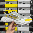 White unisex sneakers with yellow and black side logo, lace-up and chunky sole