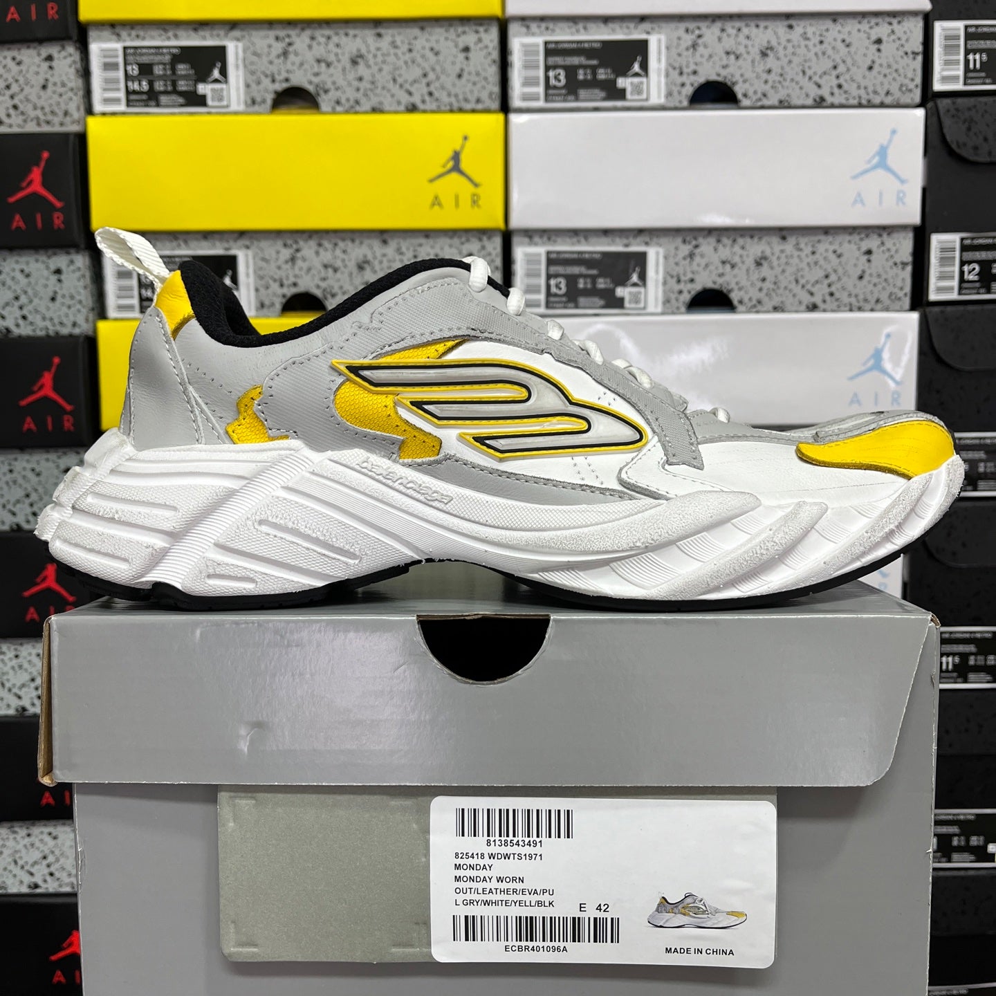 White unisex sneakers with yellow accents and large side logo, black inner lining