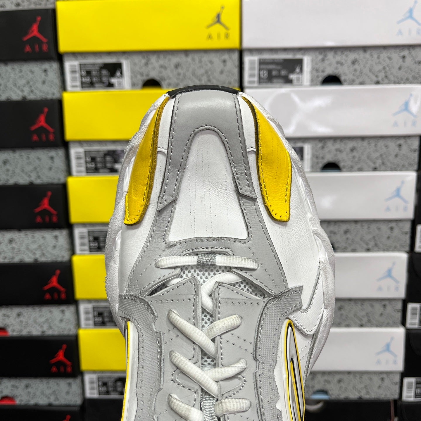 White unisex sneakers with yellow heel tabs and lace-up front, black sock lining