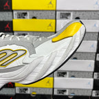 White sneaker with yellow side logo and ribbed sole detail, angled heel view