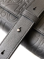Close-up of dark Dior leather with stitching lines and metal snap at strap end