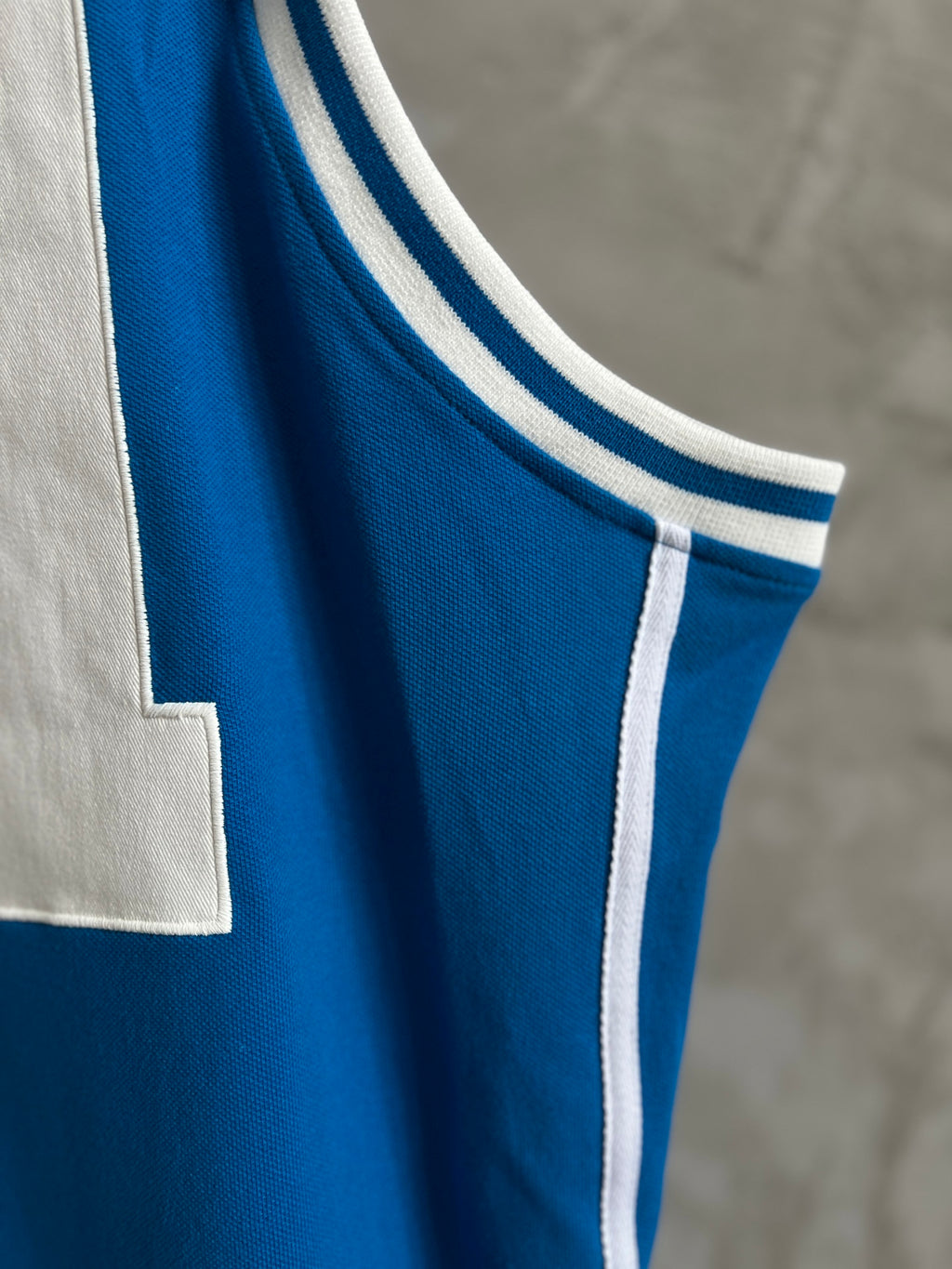 Blue sleeveless jersey with white ribbed collar and double stripe trim