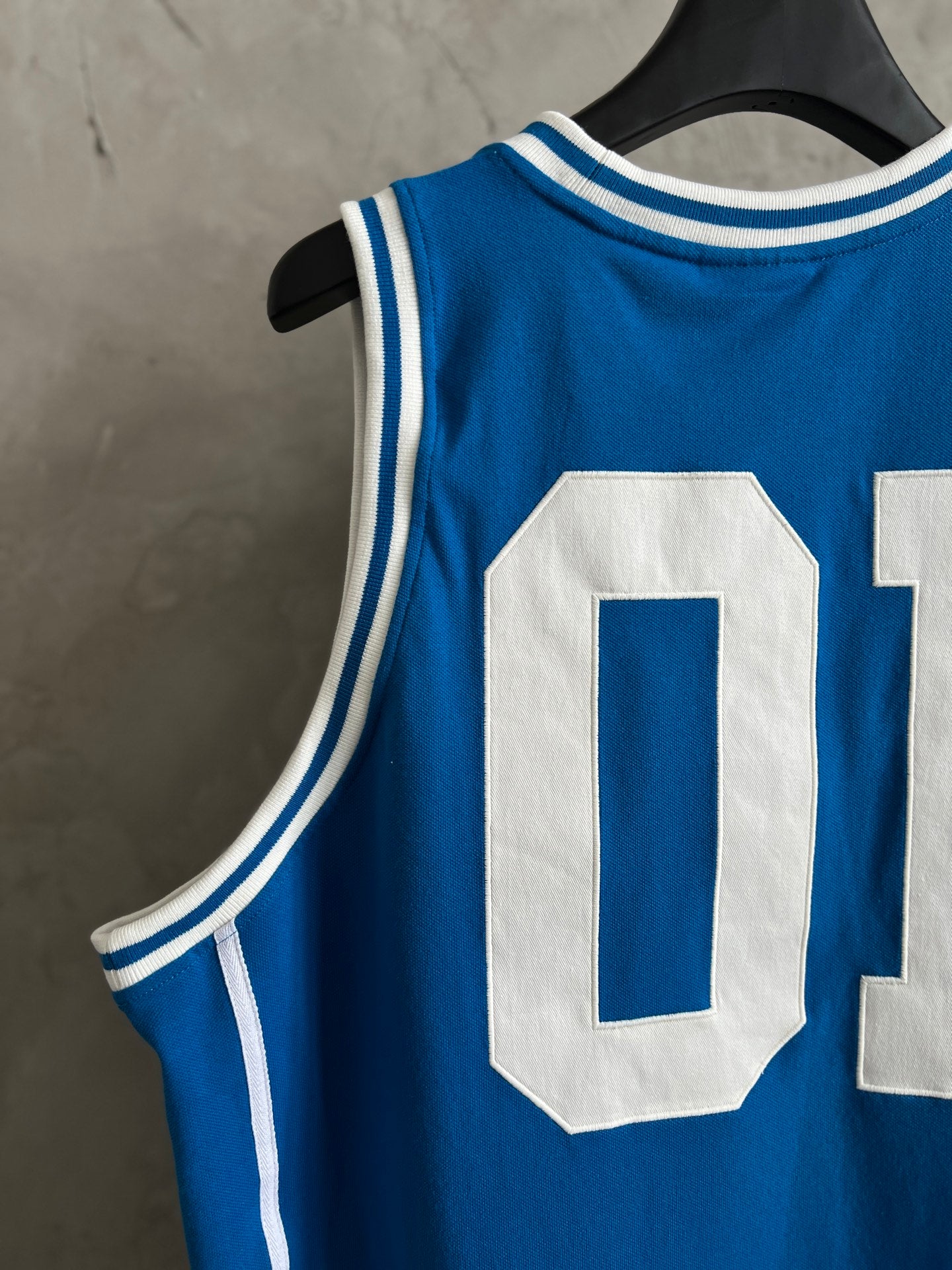 Blue sleeveless jersey with large white “0” applique and white stripe trim