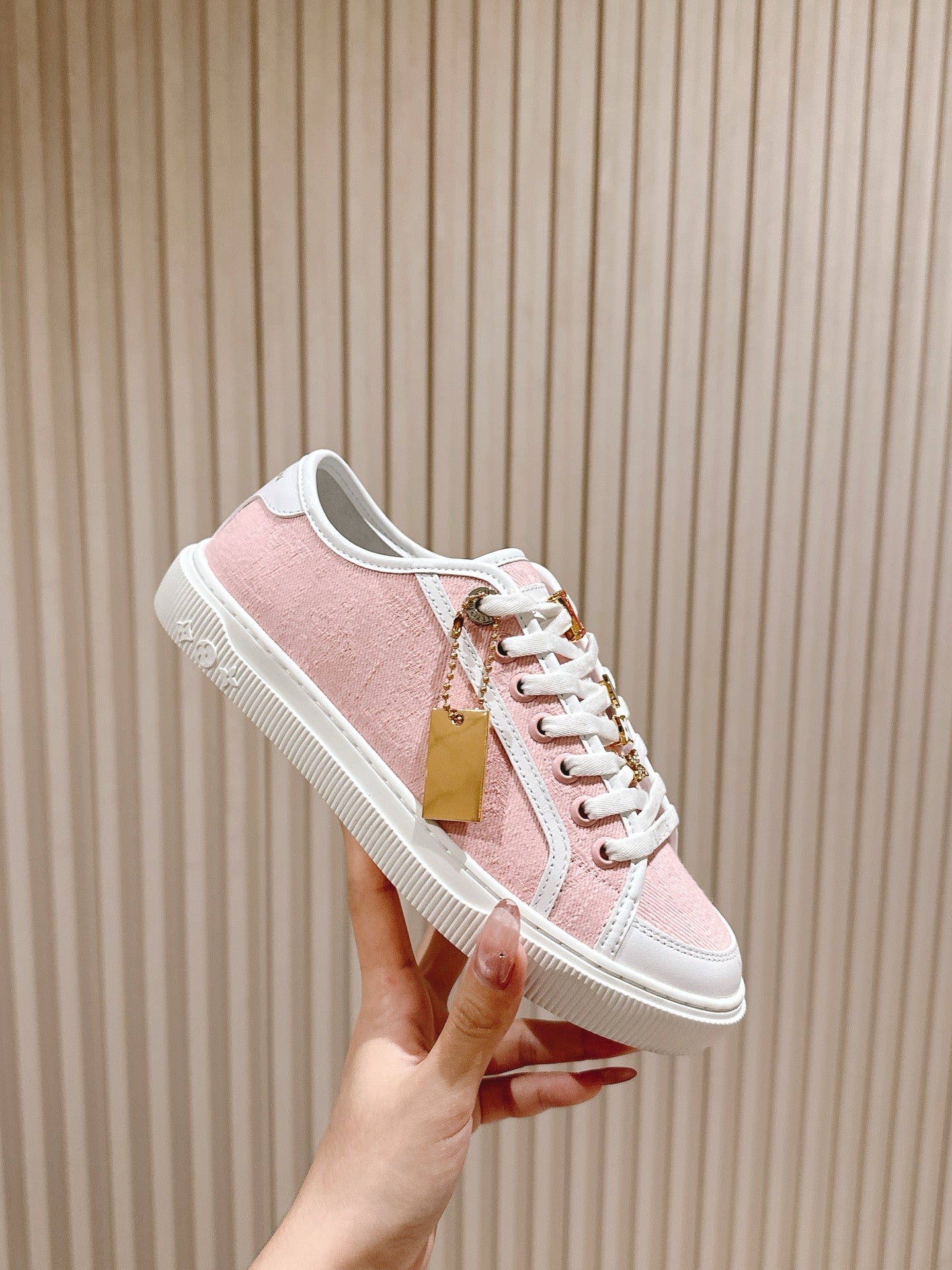 Pink and white low-top sneaker with hanging tan tag and white laces