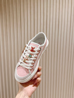 Pink and white low-top sneakers with multicolor lace eyelets and Louis Vuitton mark