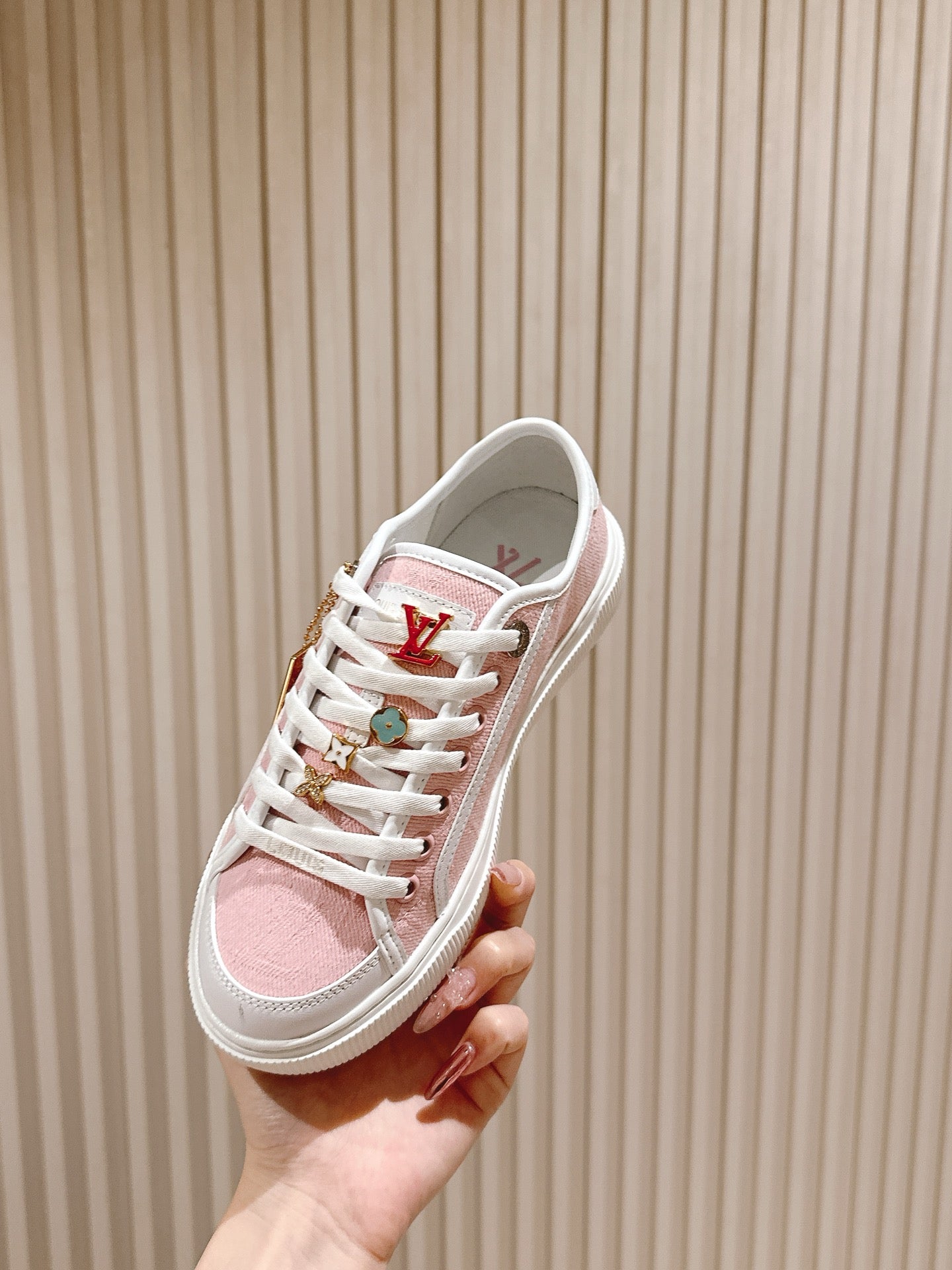 Pink and white low-top sneakers with multicolor lace eyelets and Louis Vuitton mark