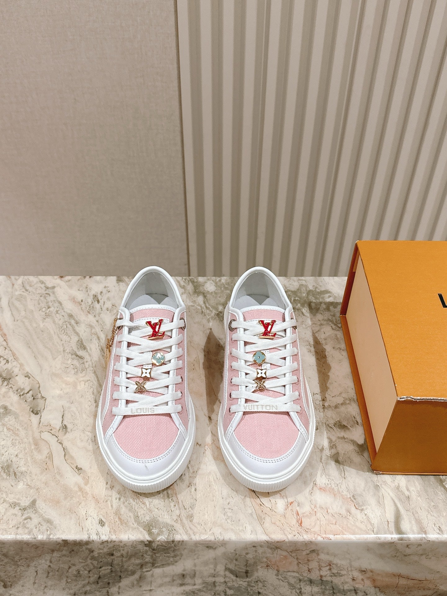 Pink and white low-top sneakers with white laces and Louis Vuitton side stripe