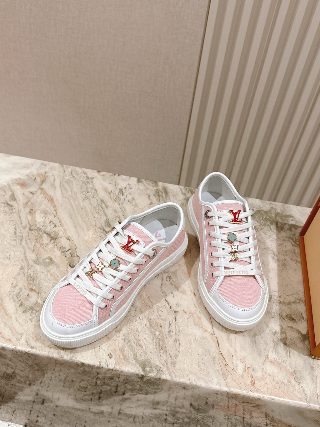 Pink and white low-top sneakers with white laces and Louis Vuitton side stripe