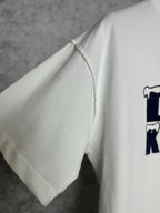 White T-shirt left sleeve with stitched cuff and partial navy graphic
