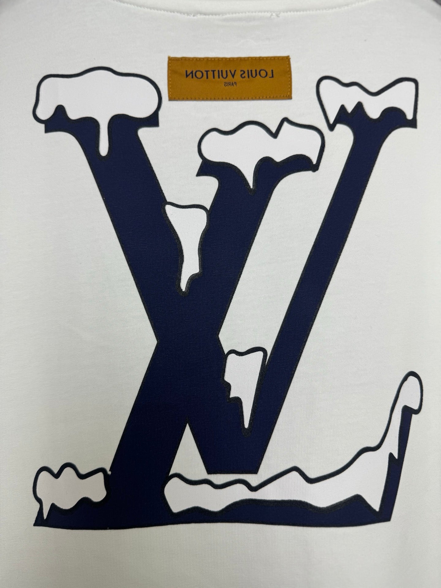 White T-shirt close-up of navy "LV" logo graphic