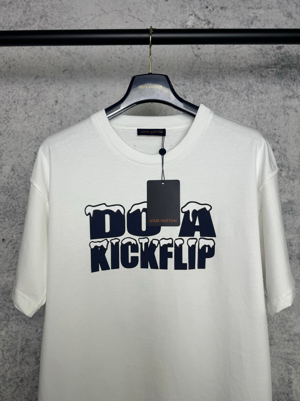 White T-shirt front with navy "DO A KICKFLIP" graphic and attached hanging tag