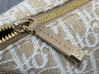Dior monogram bag close-up of zipper and leather tab with gold-tone pull