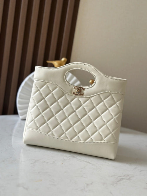 Chanel quilted cream handbag with oval handle, stitched edges, and gold-tone hardware