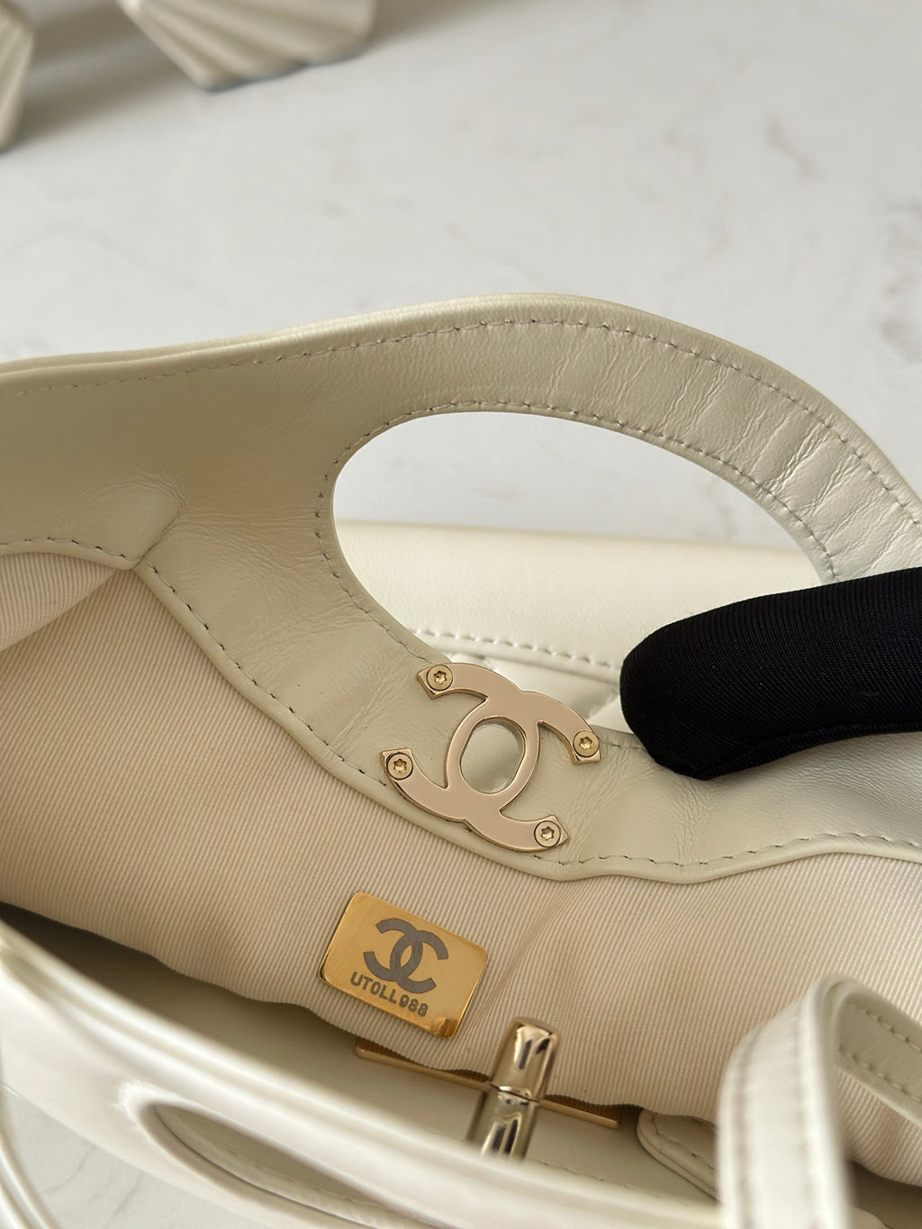 Chanel cream handbag close-up with gold-tone turnlock and interior Chanel logo patch