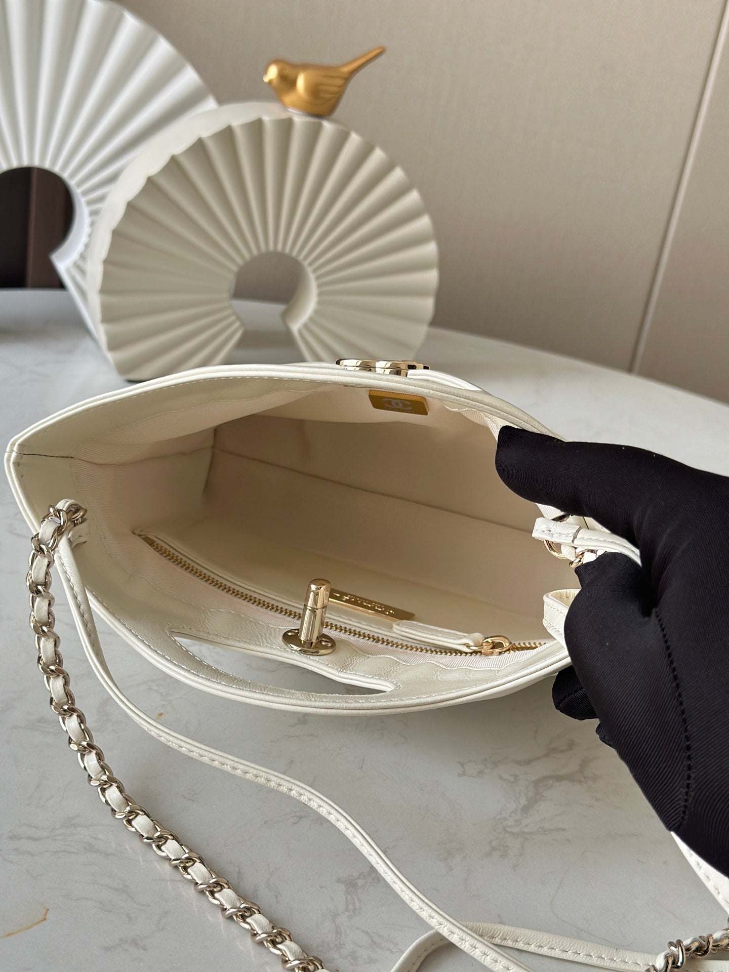 Chanel cream handbag open interior with gold-tone clasp hardware and chain strap