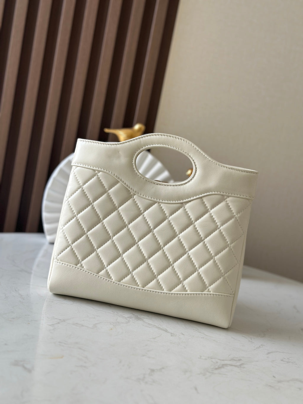 Chanel quilted cream handbag with oval handle opening and gold-tone hardware