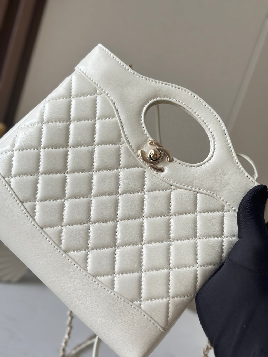 Chanel cream quilted handbag front close-up with oval handle opening and gold-tone clasp