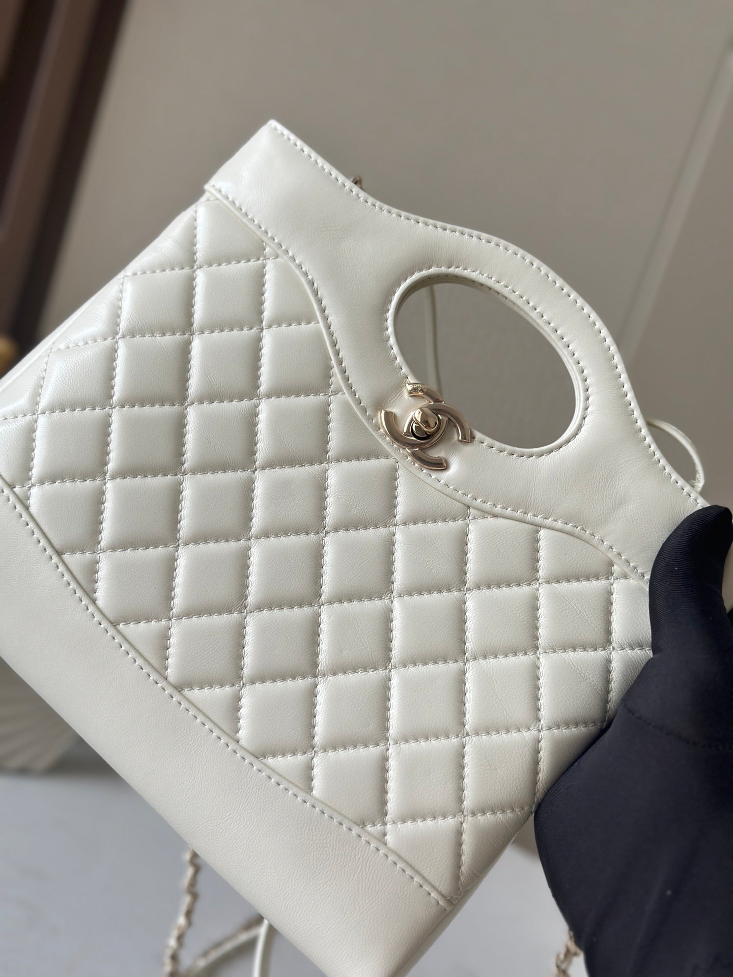 Chanel cream quilted handbag front close-up with oval handle opening and gold-tone clasp