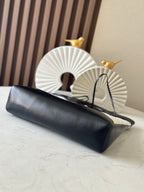 Chanel leather handbag with dark body, chain strap beside it on a table