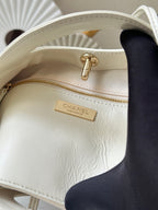 White Chanel handbag interior label on zip pocket with gold zipper pull.