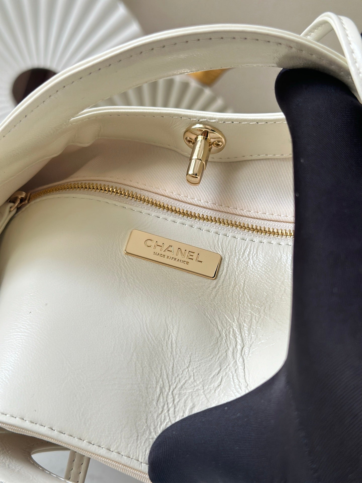 White Chanel handbag interior label on zip pocket with gold zipper pull.