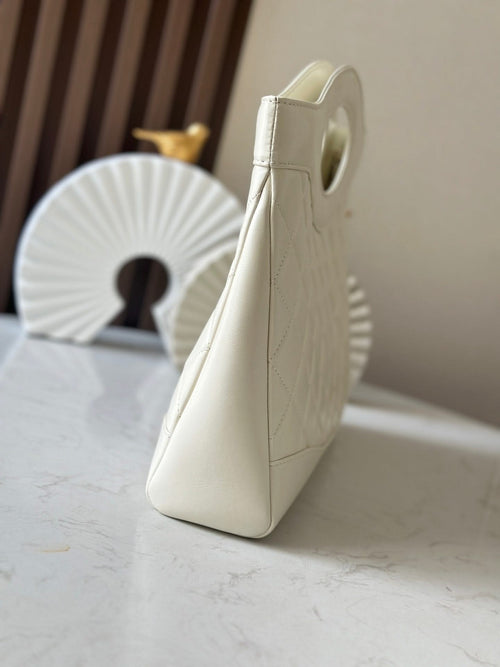 White quilted Chanel handbag with top handle and structured side profile.