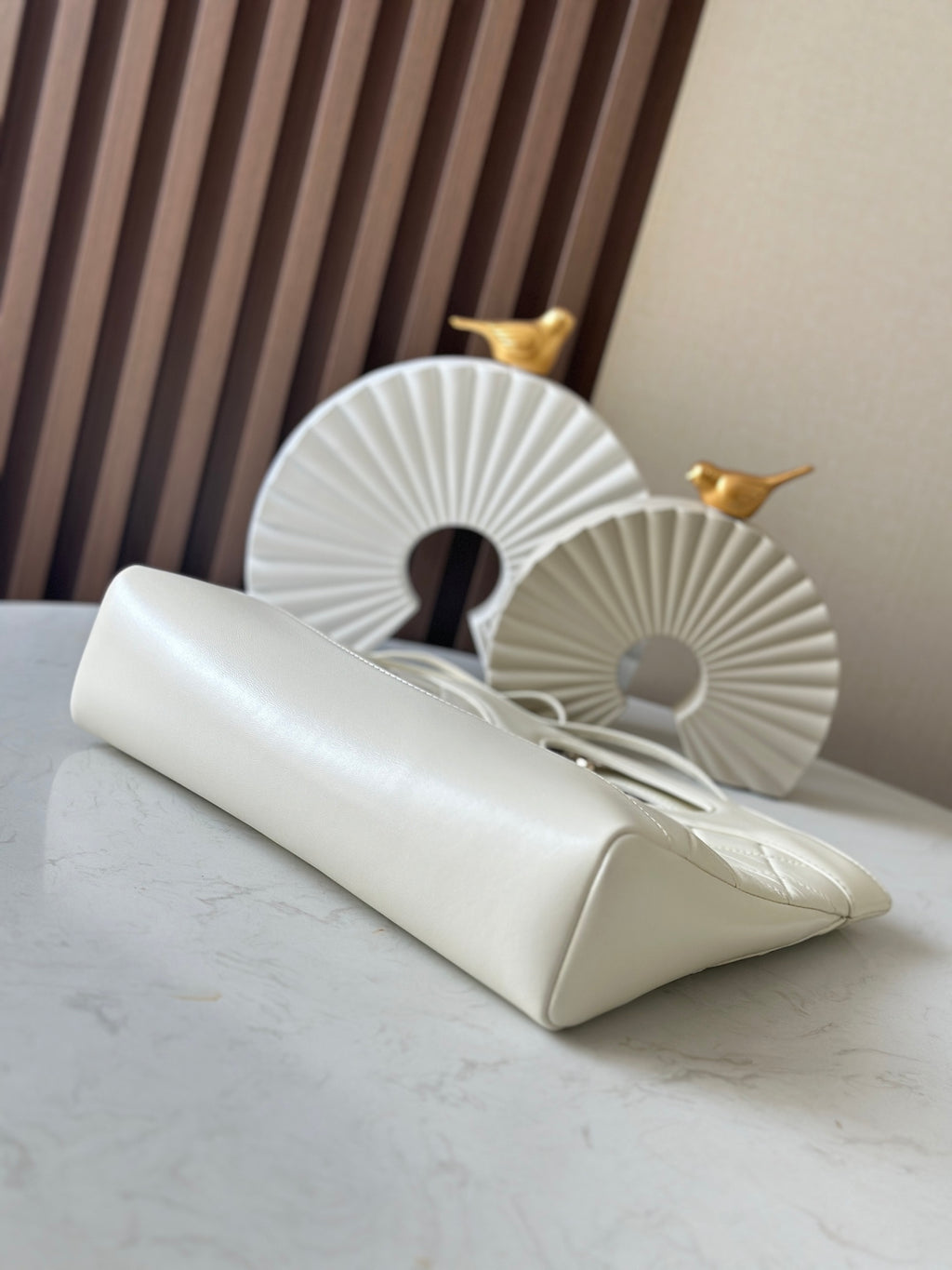 White Chanel flap bag with chain strap and gold hardware, angled side view.