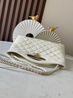 White quilted Chanel flap bag with gold clasp and chain strap.
