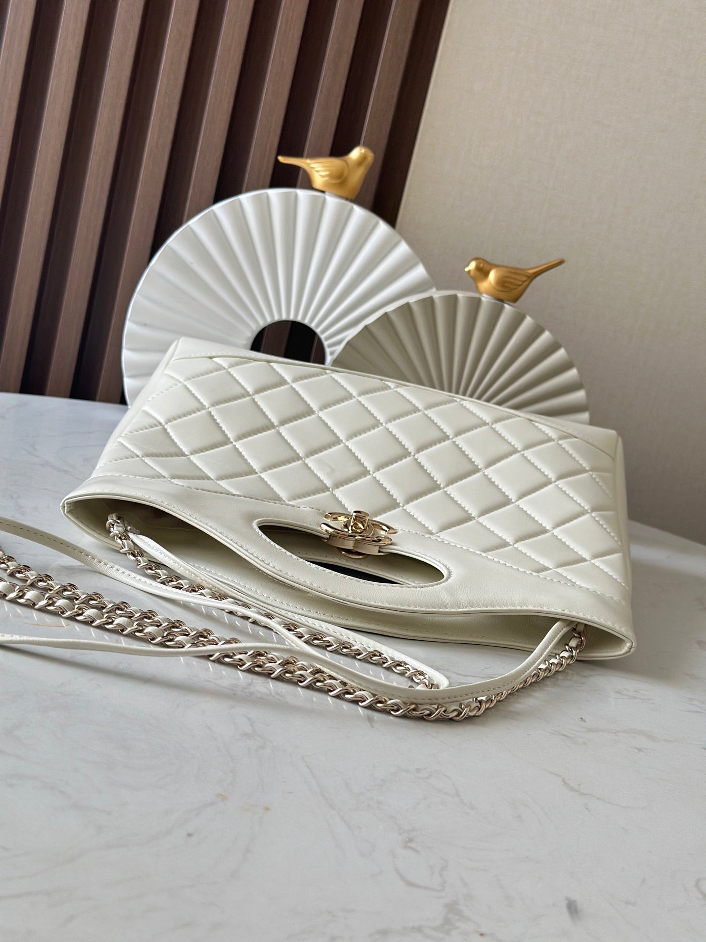 White quilted Chanel flap bag with gold clasp and chain strap.