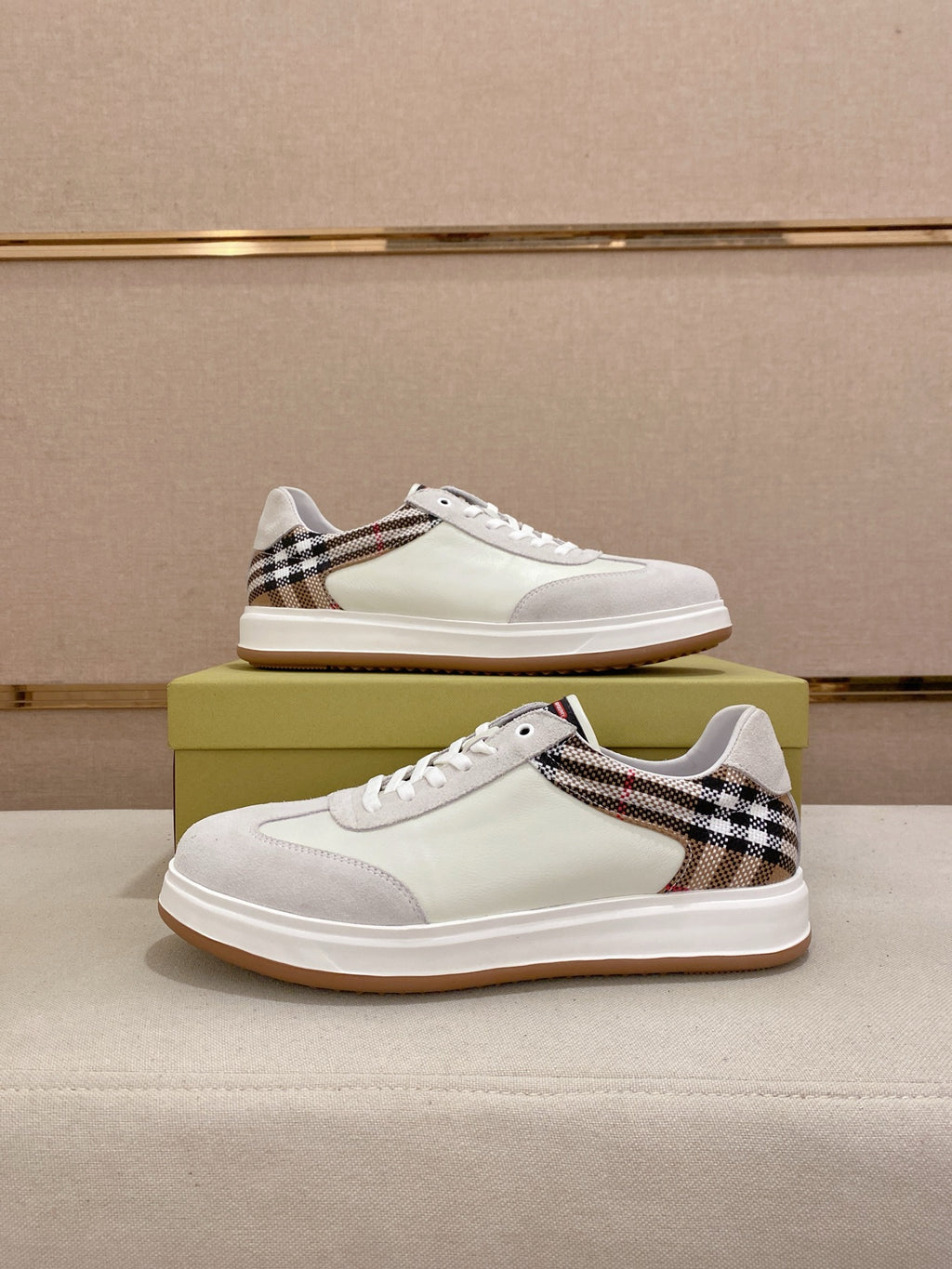 Pair of white low-top sneakers with Burberry plaid trim and gum soles