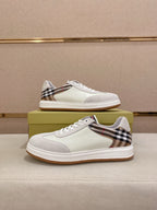 Pair of white low-top sneakers with Burberry plaid trim and gum soles