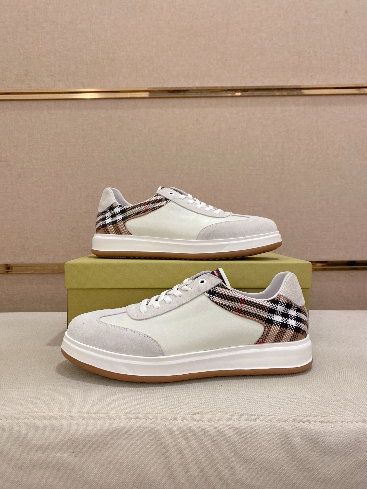 Pair of white low-top sneakers with Burberry plaid trim and gum soles