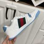 Gucci unisex sneaker side view held in hand, white upper with green-red stripe and blue sole