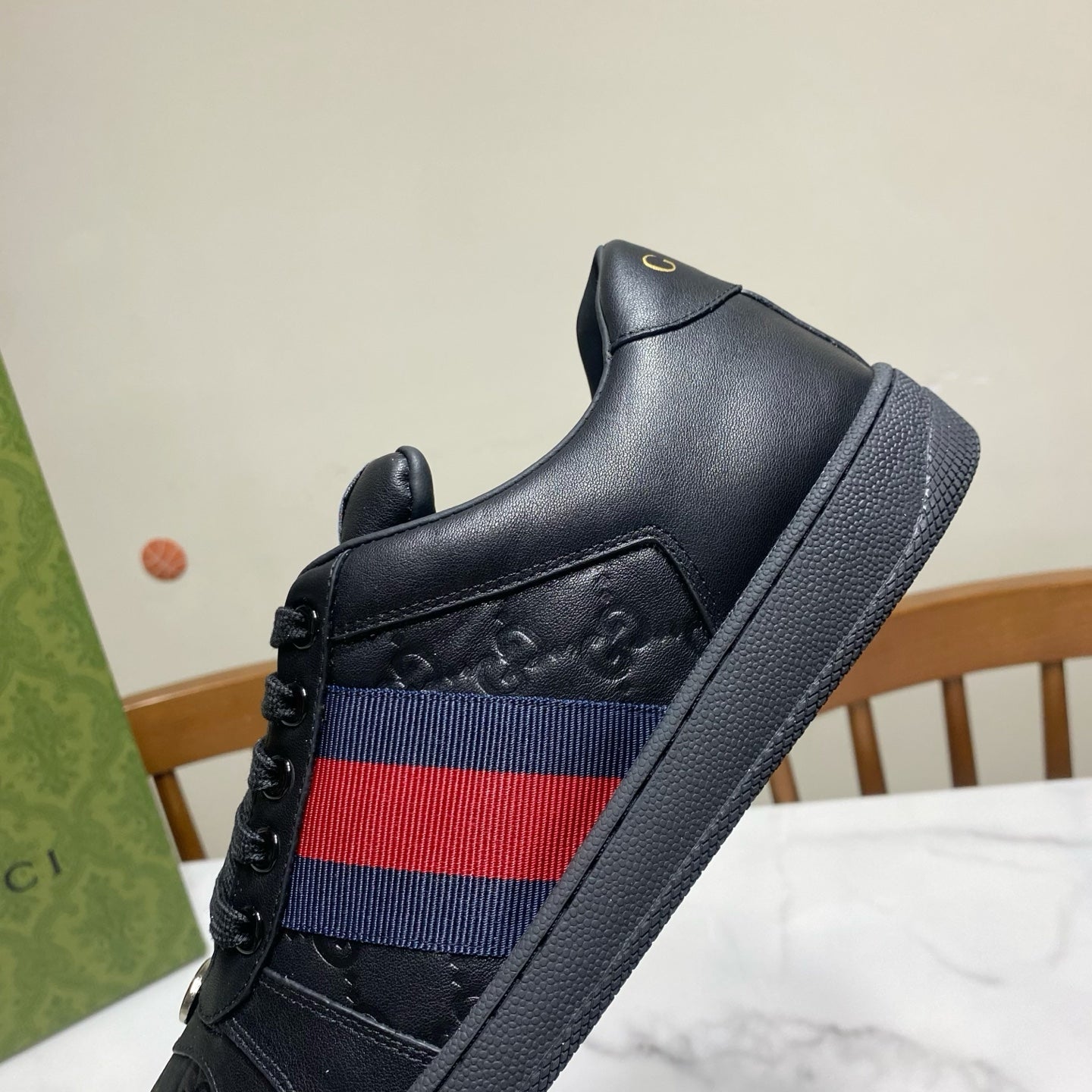 Gucci unisex sneakers, close-up side; black leather with red-and-blue web stripe.