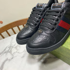 Gucci unisex sneakers, front view; black leather with red-and-blue stripe and branded tongue.