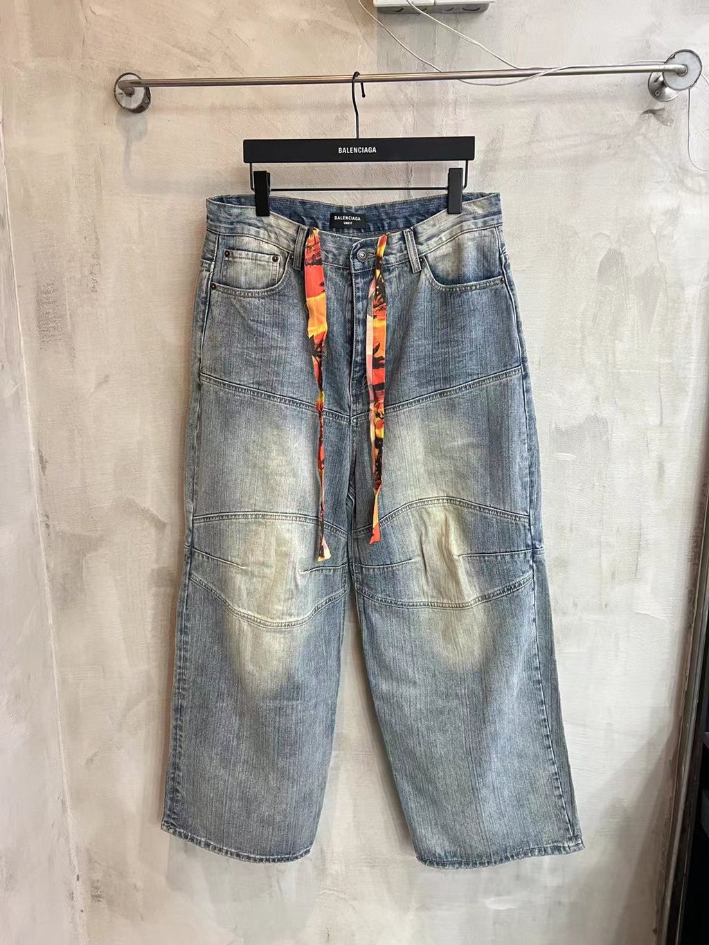 Light blue wide-leg denim pants with colorful vertical ribbon at the waist