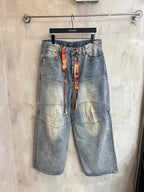 Light blue wide-leg denim pants with colorful vertical ribbon at the waist