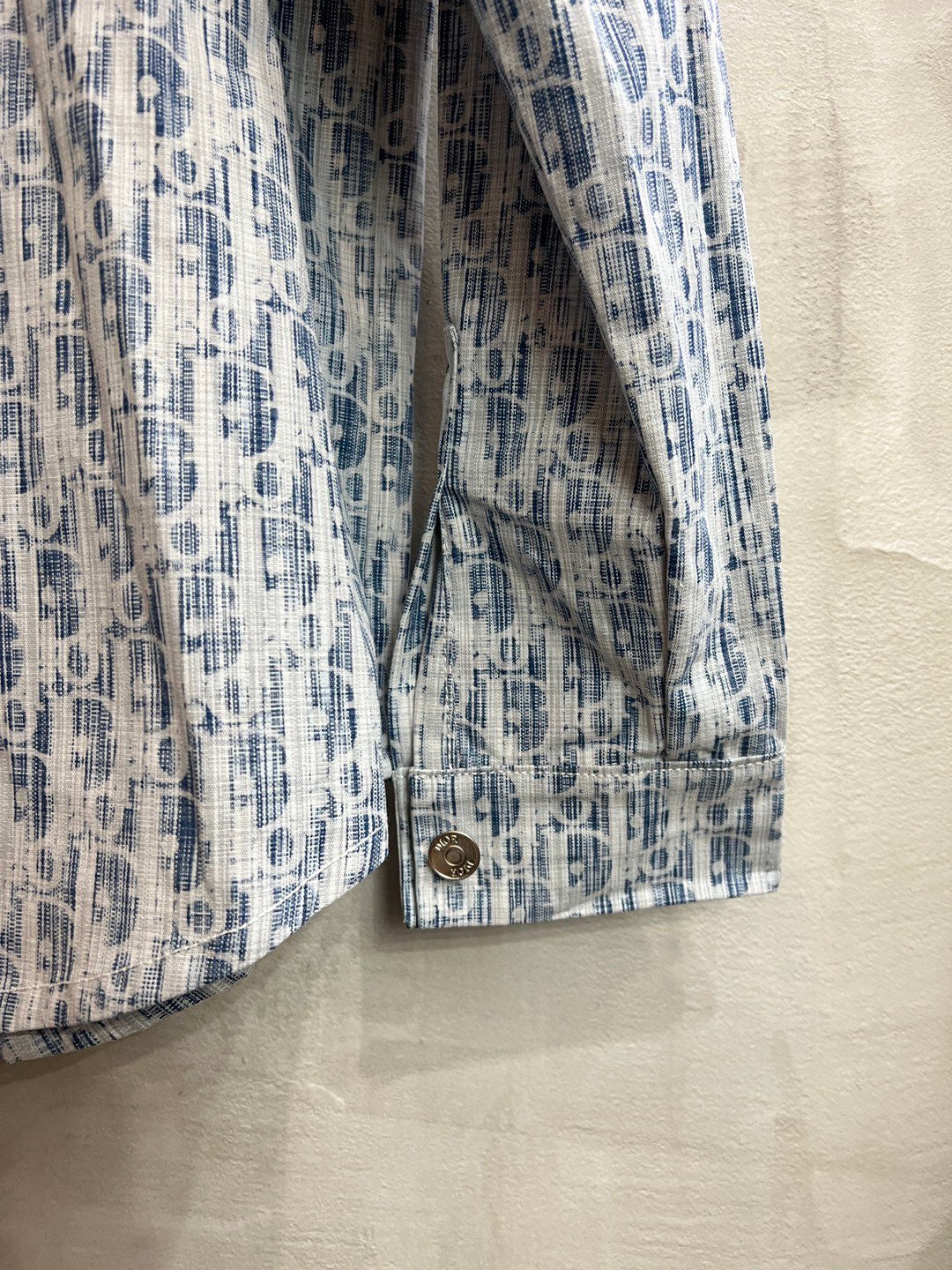 Blue-and-white patterned long-sleeve shirt cuff with stitched hem and button