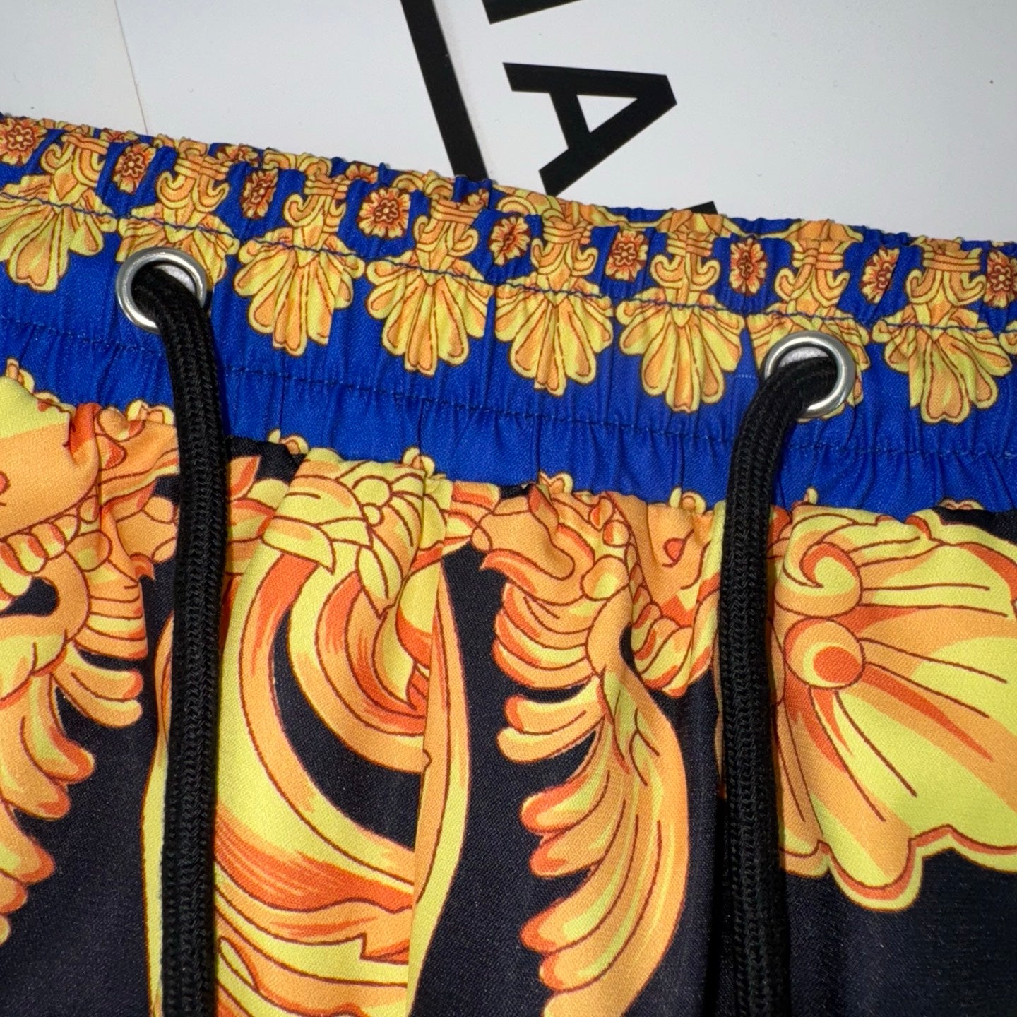 Versace printed shorts with black drawstrings and blue gold patterned waistband