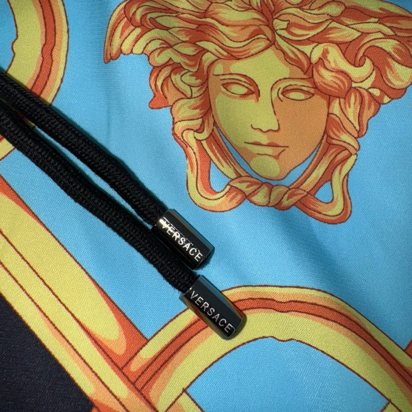 Versace fabric detail: black label tags on black trim beside blue print medallions