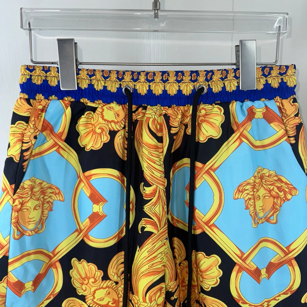 Versace shorts close-up with black, blue and gold baroque portraits and swirl patterns