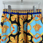 Versace shorts close-up with black, blue and gold baroque portraits and swirl patterns