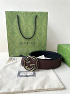Brown leather belt with circular GG buckle, shown with dust bag