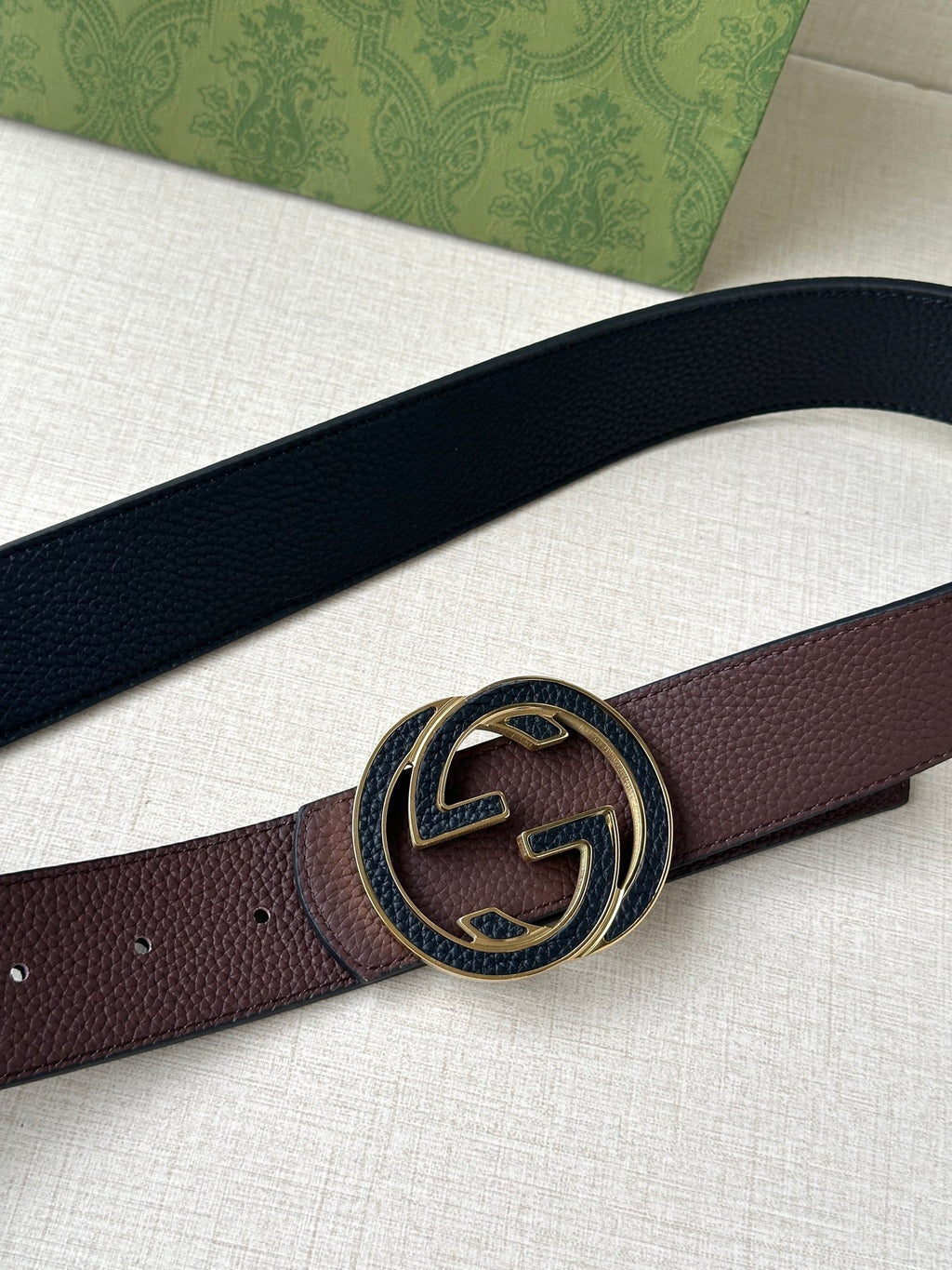 Brown leather belt close-up: circular GG buckle with gold-tone detail