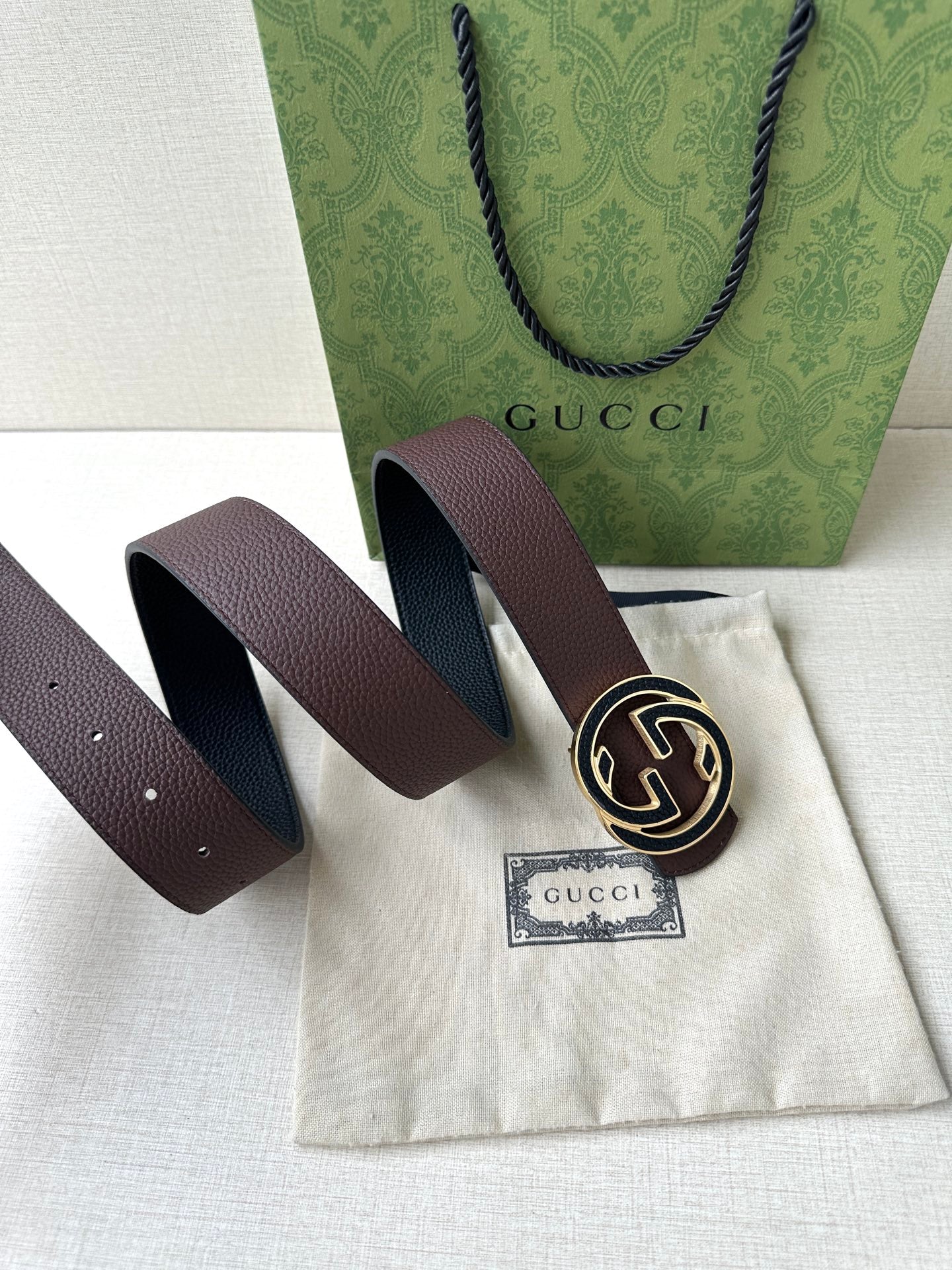 Brown leather belt laid flat with circular GG buckle and two strap ends