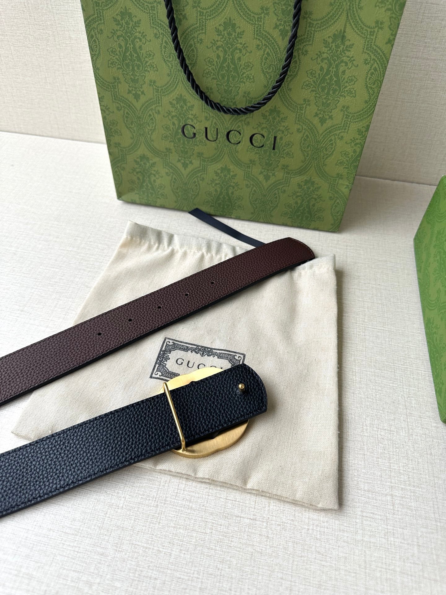 Brown leather belt with gold-toned circular buckle and adjustable strap end