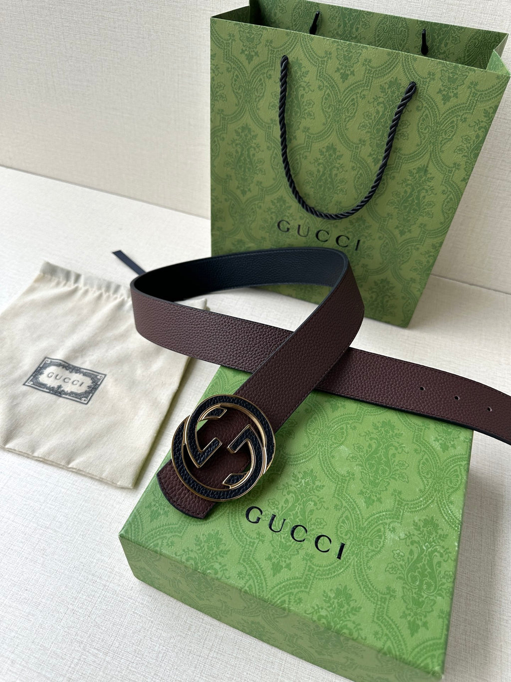 Brown leather belt with circular GG buckle, laid across packaging tissue