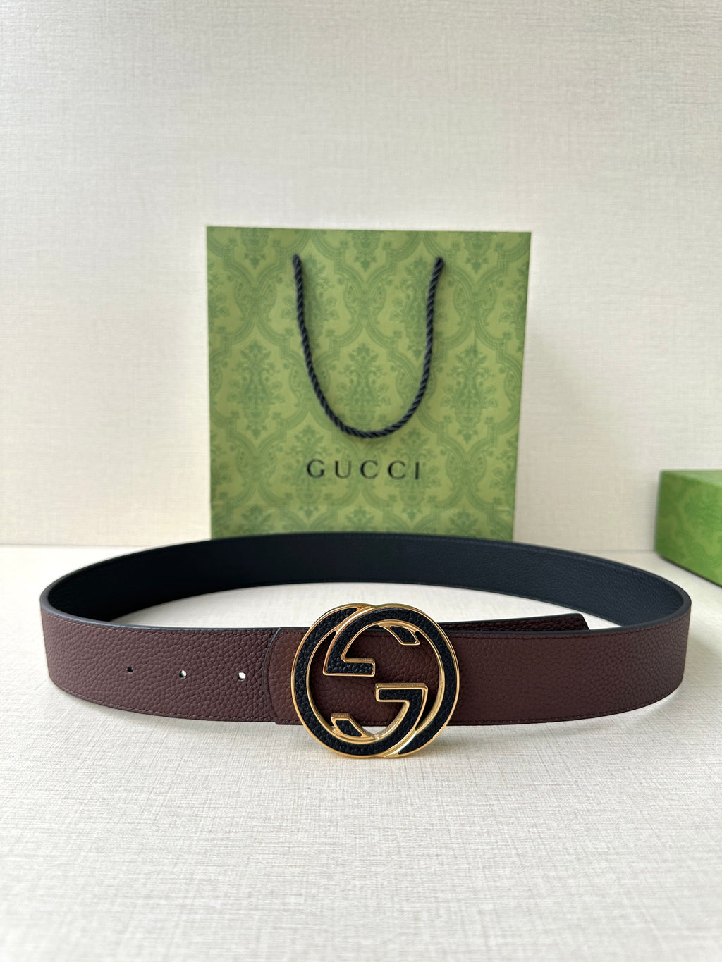 Brown leather belt with circular GG buckle, stitched strap, visible holes